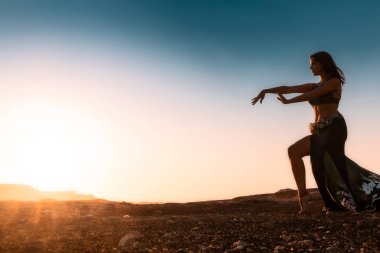 Ünlü Arap oryantal dans için dans kadın. Namibe kurak çöl düz gün batımı ile. Afrika. Angola.
