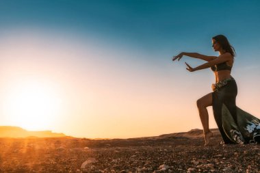 Ünlü Arap oryantal dans için dans kadın. Namibe kurak çöl düz gün batımı ile. Afrika. Angola.