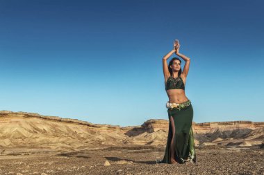 Woman dancing to the famous belly dance with natural sunset light, in the Namibe Desert with canyons. Africa. Angola. clipart