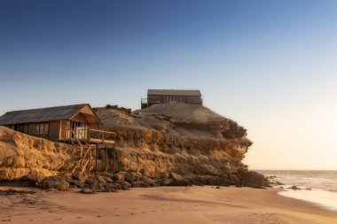Güzel gün batımı cliff ve ahşap Namibe plaj sahil şeridi ev sahipliği yapmaktadır. Afrika. Angola.