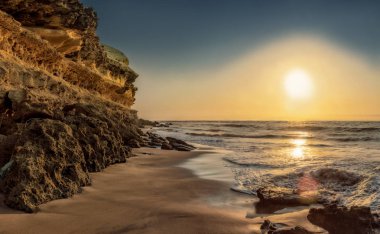 Cliff ve ıssız Namibe sahilde kayalık plaj güzel gün batımı. Afrika. Angola.