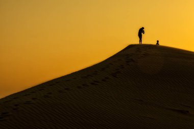 Gün batımı ile bir kumul üzerine Abu Dabi çölde eğleniyor arkadaş grubu.
