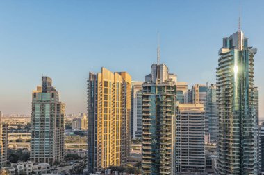 Mavi gökyüzü ve güneş pencereye yansıyan gökdelenlerin görünümü. Gün batımı ışığıyla. Uçan
