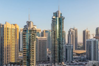 Mavi gökyüzü ve güneş pencereye yansıyan gökdelenlerin görünümü. Gün batımı ışığıyla. Uçan