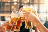 částečný pohled lidí cinkání brýle s pivo v baru 