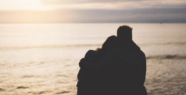 Couple hugging on background beach ocean sunrise, meeting of lovers concept, silhouette two romantic people cuddling and looking on view evening seascape, hipster enjoy sunset together, travel holidays vacation relax