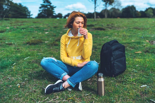 Happy girl holding in hands cup of hot tea on green grass in outdoors nature park top view, beautiful woman hipster enjoy drinking cup of coffee, lifestyle relax recreation meditation concept