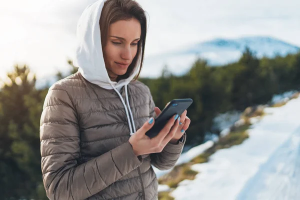 girl hold in hands mobile phone, person type message on smartphone, relax tourist travels planning trip in snow mountain, hipster enjoy winter nature, journey landscape trip, lifestyle holiday concept