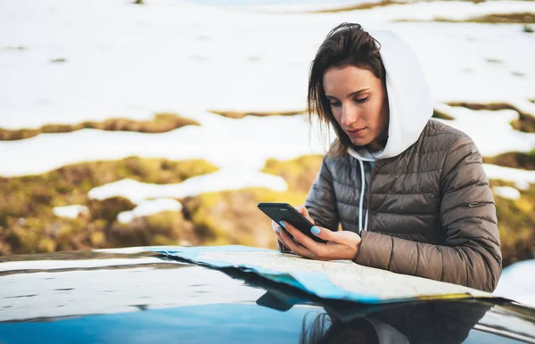 girl hold in hands mobile phone and looking on map, hipster enjoy winter nature, relax tourist travels by auto car, people planning trip in snow mountain, journey landscape trip, lifestyle holiday concept