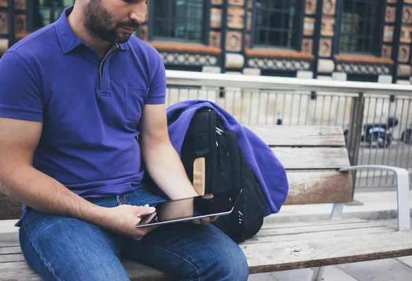 Hipster texting message on tablet computer or technology screen mockup. Smile young man using digital on building castle background. Male hands tourist holding gadget on blur cityscape