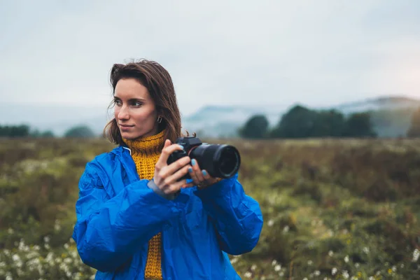 photographer tourist girl in blue raincoat hold in female hands photo camera take photography foggy mountain, traveler shooting autumn nature, video click on camera technology, journey landscape vacation concept free space