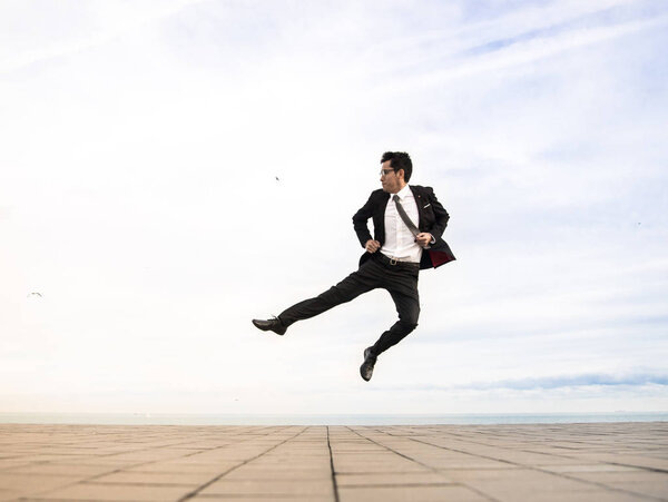 young man wearing a suit and jumping outdoor