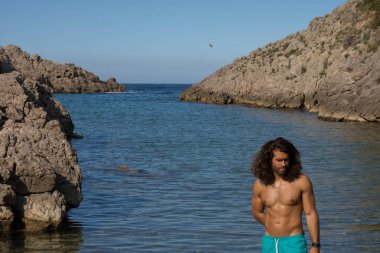 Genç kaslı adam mavi kayalık deniz defne poz