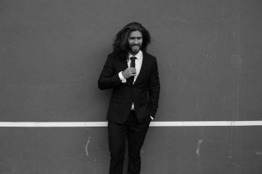 Siyah elbiseli gri arka plan üzerinde poz acımasız sakallı adam