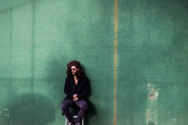 Yeşil duvar üzerinde siyah palto poz çıplak gövde ile genç adam