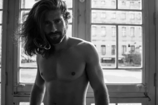 Genç adam yaşlı vintage pencerenin önünde poz çıplak gövde ile sakallı 