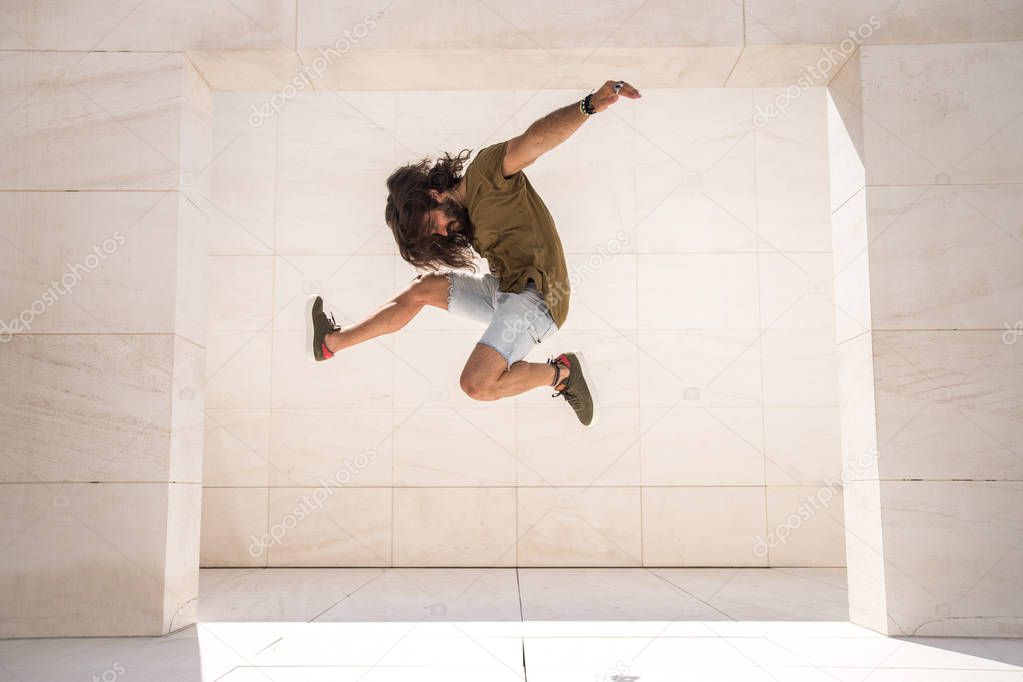 Young sporty man jumping extremely high in limestone building 