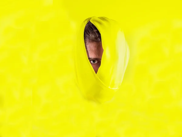 Male head wrapped in yellow fabric on yellow background