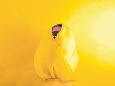 Male head wrapped in yellow fabric on yellow background clipart