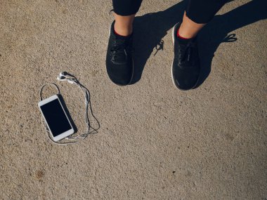 sporcumuz smartphone kulaklık ile yakın duran spor ayakkabı içinde kırpılmış görünümünü 