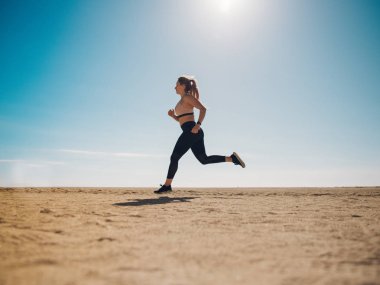 çekici jogger güneş ışığı ile kumlu plaj üzerinde çalışan