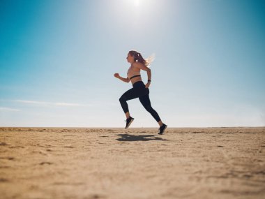 güzel sporcumuz güneş ışığı ile kum plajındaki koşu