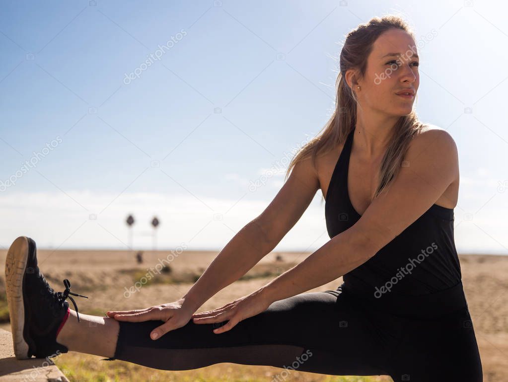 beautiful athletic girl stretching leg outdoors