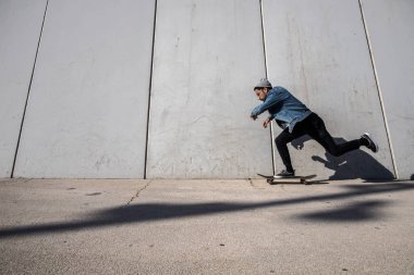 male skater skateboarding near wall at urban place clipart