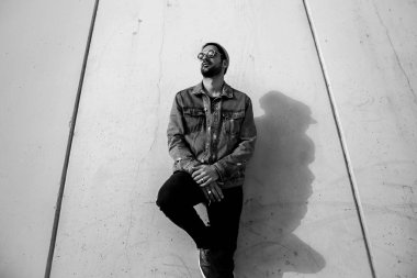 Trendy denim ceket, duvar, siyah ve beyaz fotoğraf yakın güneş gözlüğü ve şapka poz şık adam 