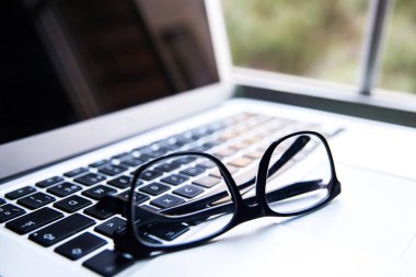 Üzerinde siyah gözlük ile modern gümüş laptop