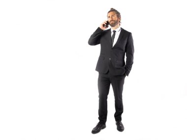 siyah takım elbiseli yakışıklı genç işadamı beyaz izole telefonla konuşurken