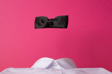 Beyaz gömlekli, pembe arka planda siyah papyon.