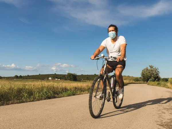 Młody Człowiek Rowerze Wiejskiej Drodze Masce — Zdjęcie stockowe