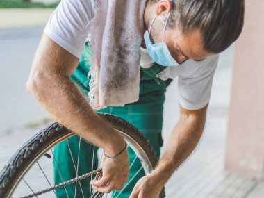 Bir tamirci maske takarak bisiklet tamir etmeye çalışıyor.