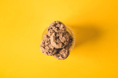 Bir bardağın içinde sarı arka planda çikolatalı kurabiyeler. 