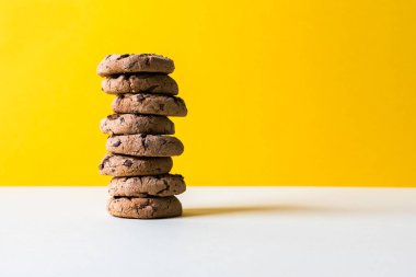 Sarı arka planda çikolata parçacıklı kurabiye kulesi.