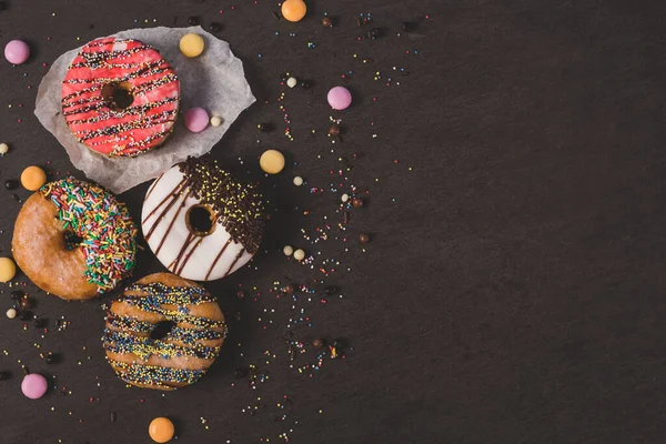 Rosquillas Colores Con Algunos Caramelos Una Mesa Negra Fotos De Stock Sin Royalties Gratis