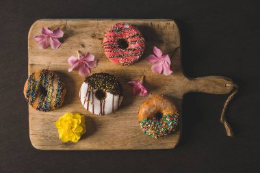 Ahşap bir masada siyah arka planı olan renkli çörekler.