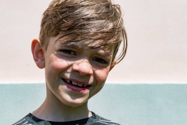 Güneşli bir günde küçük bir çocuk evin avlusunda suyla yıkanır.