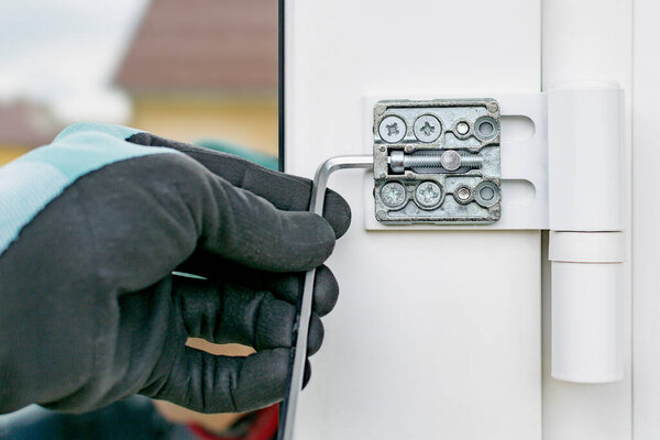 Работник в перчатках регулирует установленную пластиковую дверь

