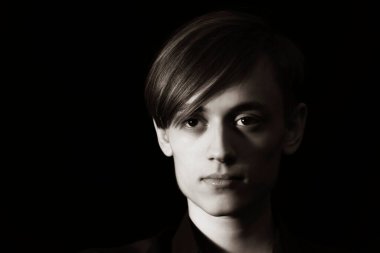 Karanlık bir arka planda genç bir adamın portresi