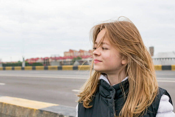 A young girl on a road bridge looks into the distance