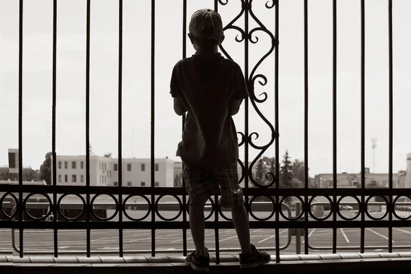 Ένα Μικρό Αγόρι Κοιτάζει Στάδιο Μέσα Από Ένα Μεταλλικό Φράχτη — Φωτογραφία Αρχείου