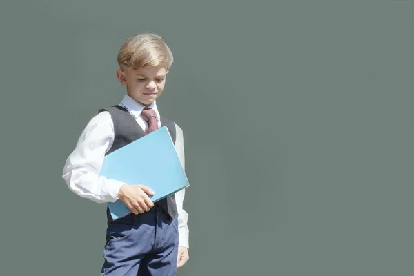 手に本を持って制服を着た小さな男の子が学校の準備をしています — ストック写真