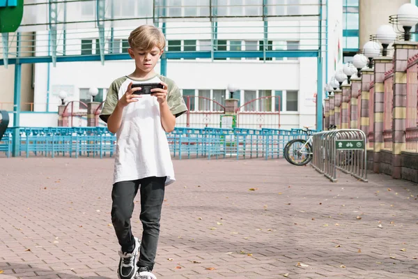 Een Kleine Jongen Onderweg Speelt Zijn Telefoon Terwijl Hij Door — Stockfoto