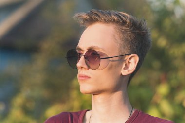 Gün batımında gözlüklü genç bir adam. Kameraya poz veriyorum.