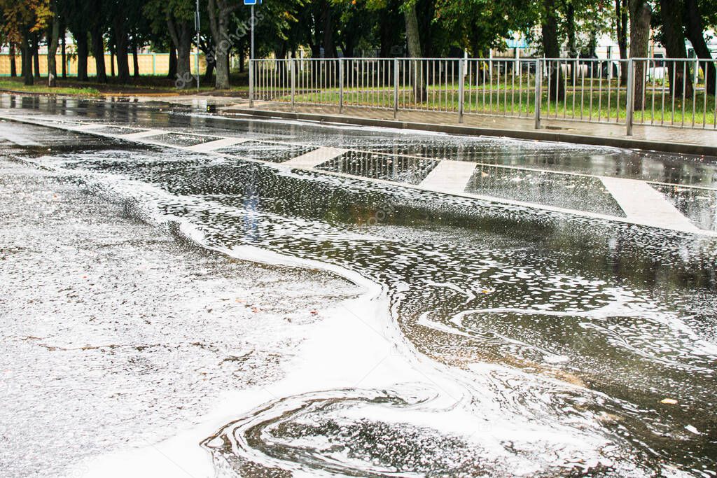 Water with foam from a chemical substance flows along a city road