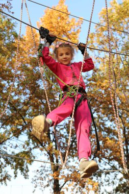 Küçük kız ağaçlardaki ip engellerinin üstesinden geliyor.