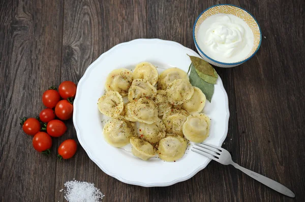 Knoedels op een houten tafel met kruiden tomaten — Stockfoto