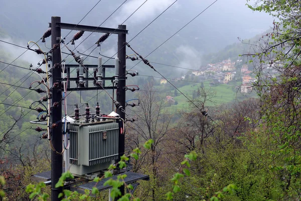 High-voltage substation transformer on mountains and fog clouds
